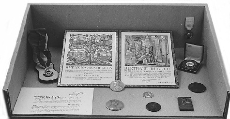 Description: Several of Russell's prestigious awards are here displayed together. Among them, the Order of Merit (top left) and the related certificate signed by King George VI (bottom left), the Nobel Prize for Literature (top centre) and the accompanying medallion (at base of certificate). Archive Box Number: NA